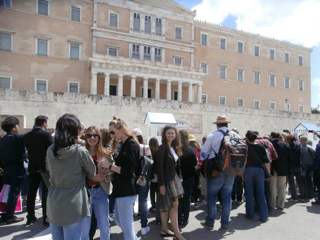 Locals and tourists alike gather to witness the change of the guard ceremony at Syntagma Square, in front of the Parliament.