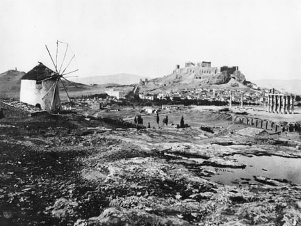 In this old photograph, left to right: The Philopappos Monument, the Weiler building which now houses the administration for the Acropolis Museum, the Acropolis, the ruins of the Temple of Olympian Zeus and closer to us the banks of the River Ilissos and the building that was built over the Temple of Agrotera Artemis.